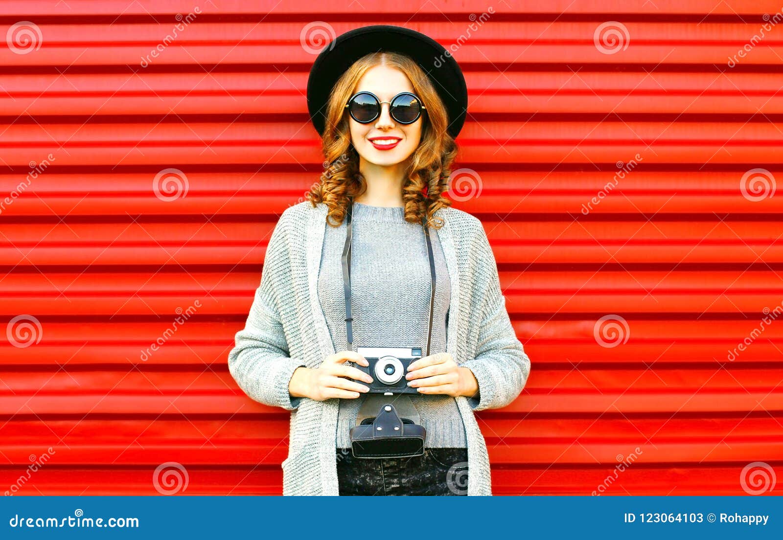 pretty autumn happy girl holds retro camera on red background