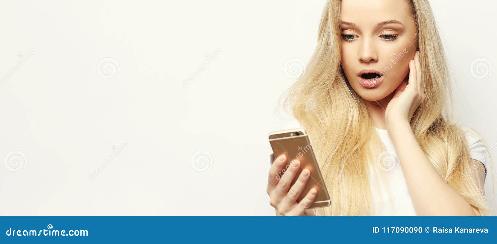 pretty blond woman with long hair holds modern smart phone, recieves unexpcted message from friend, reads reminder