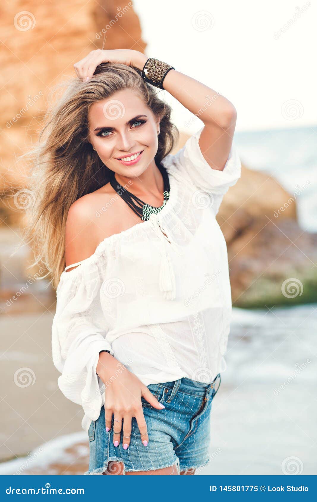 Pretty Blonde Girl With Long Hair Is Posing To The Camera On The Be