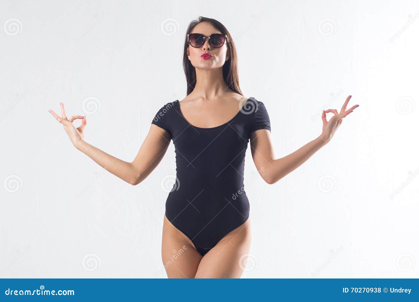pretty brunette with long hair, wearing black one piece swimwear, holding hands aside, imitating meditation, making duck