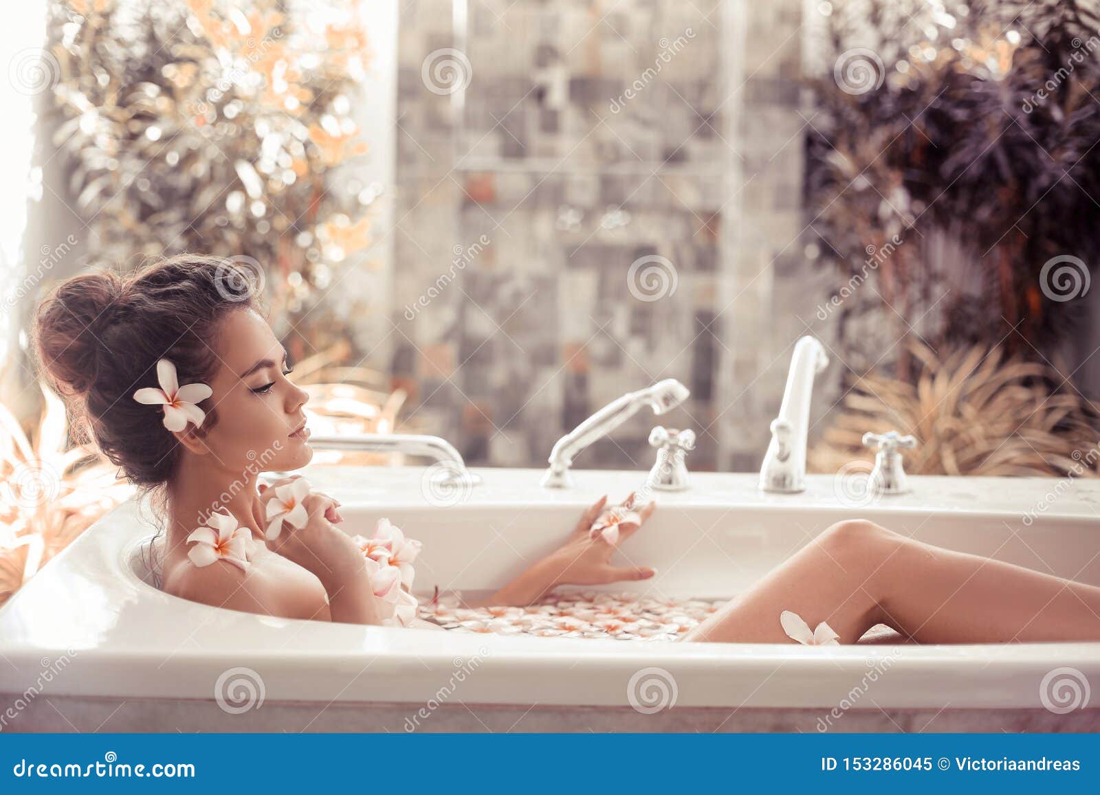 pretty girl enjoying bath with plumeria tropical flowers. health and beauty. spa relax. closeup beautiful woman bathing with