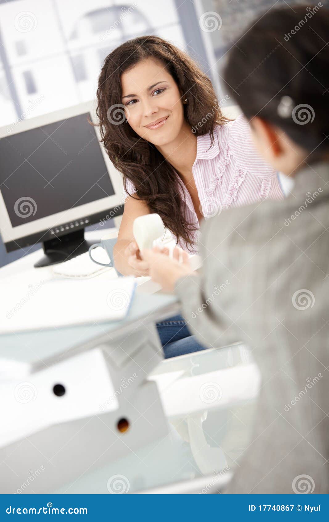 pretty girl passing phone to colleague in office
