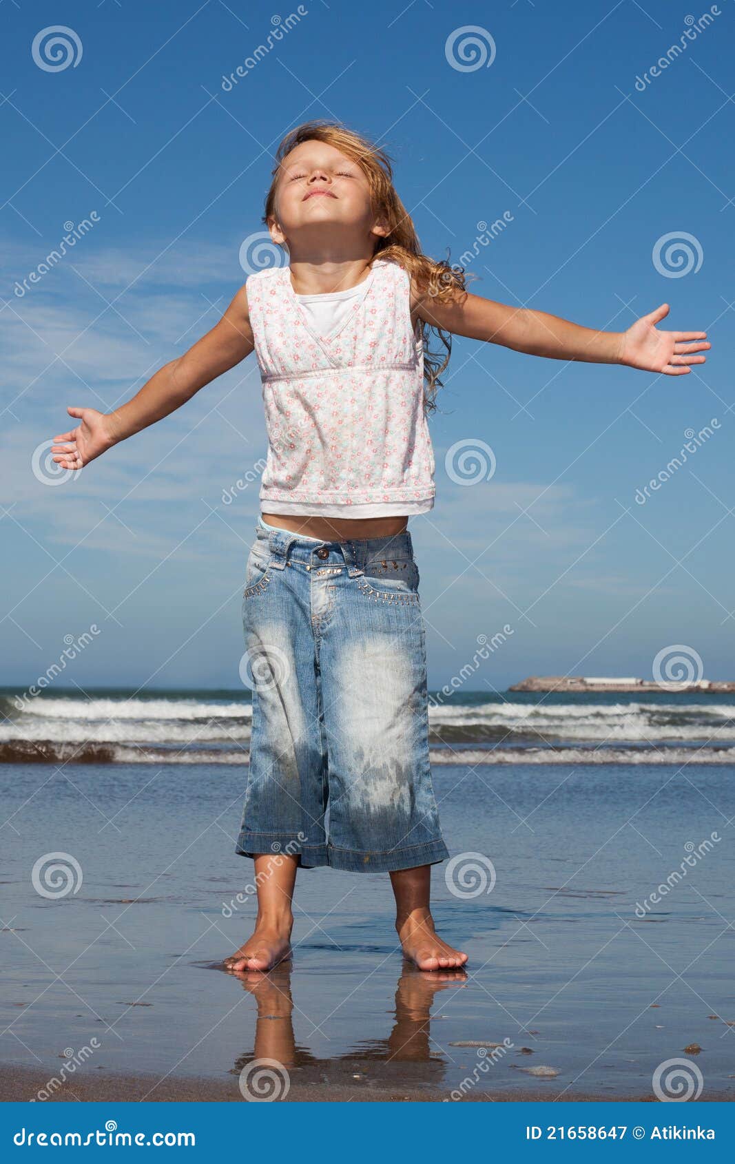 pretty little girl with arms wide open on the beach