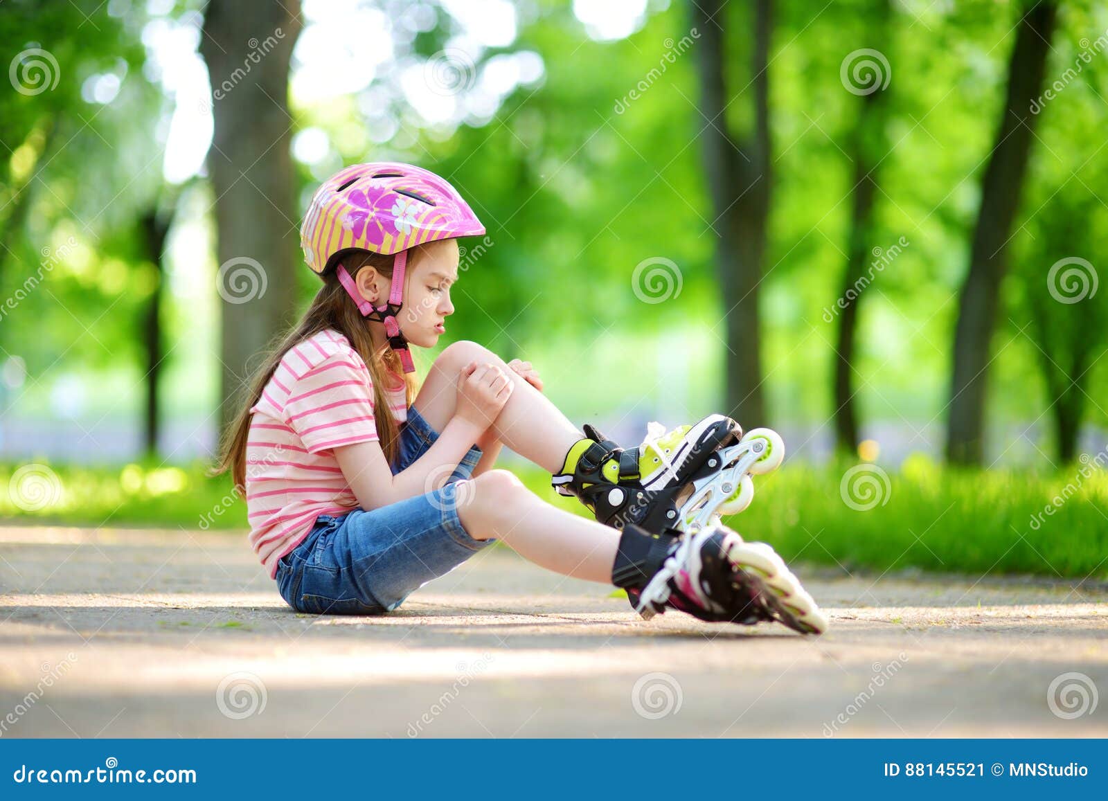 pretty little girl learning to roller skate on beautiful summer day in a park
