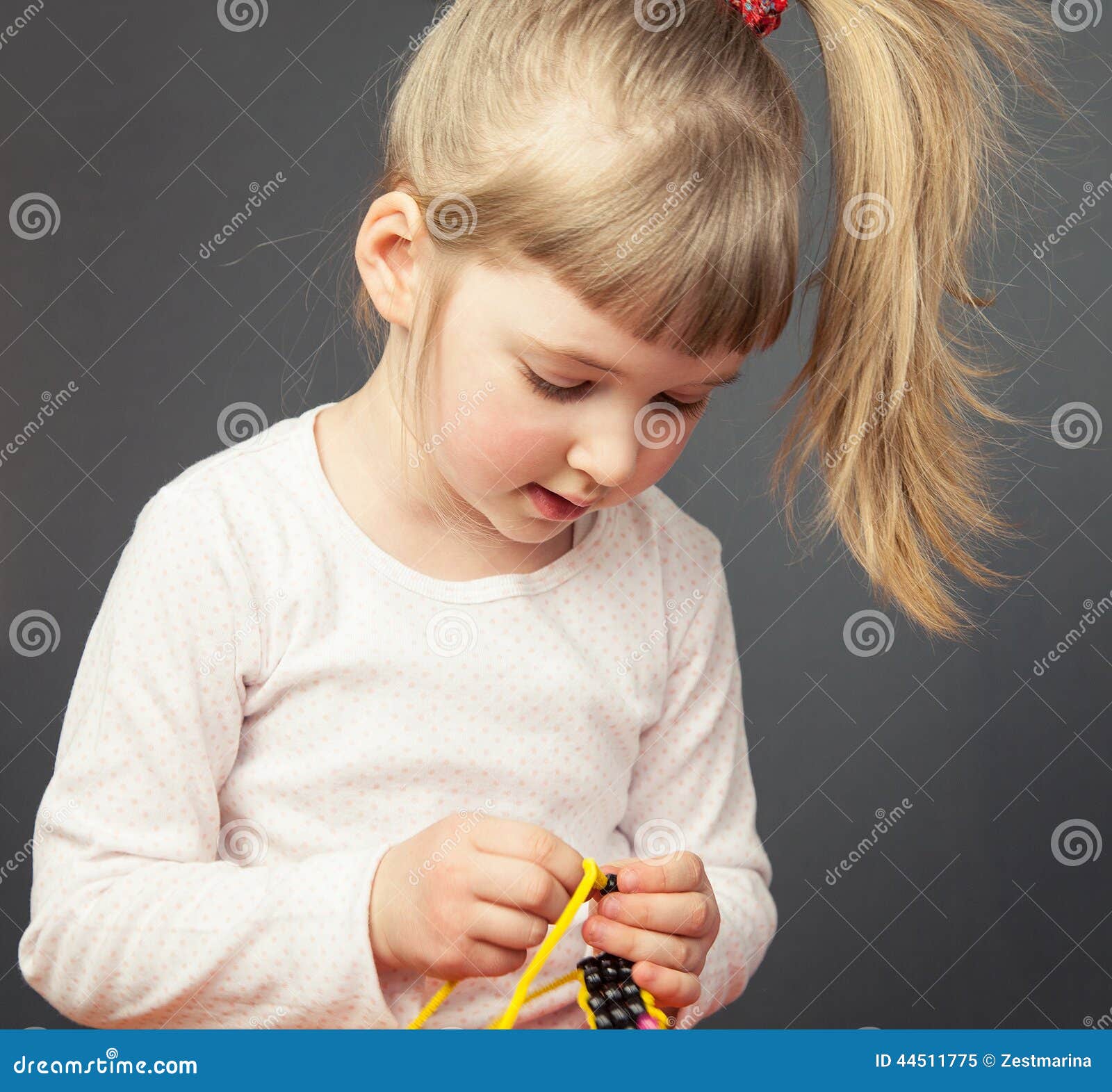 Pretty Little Girl Threading Beads on an Yellow Wire Stock Image ...