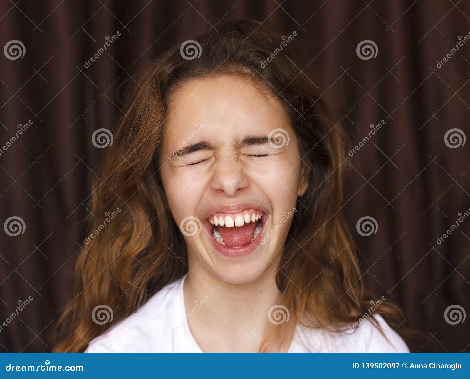 Pretty Teenager Girl With Long Hair Makes Very Funny Face And Laughing With Closed Eyes Stock