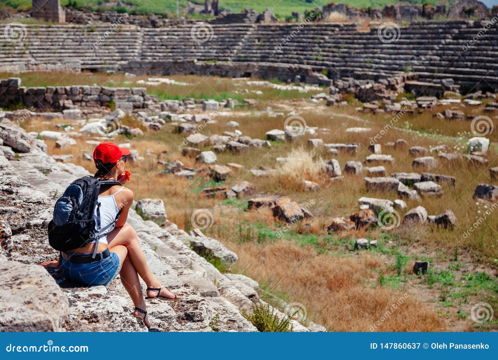 pretty tourist woman with backpack at the ruins of ancient city of perge near antalya turkey