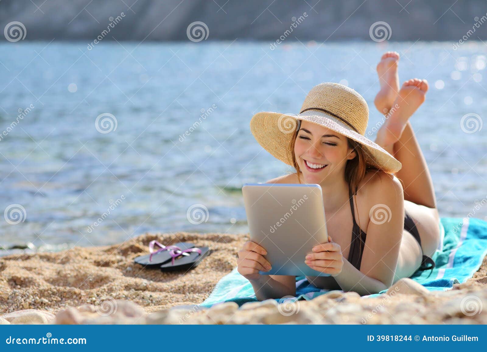 pretty woman reading a tablet reader on the beach on vacations