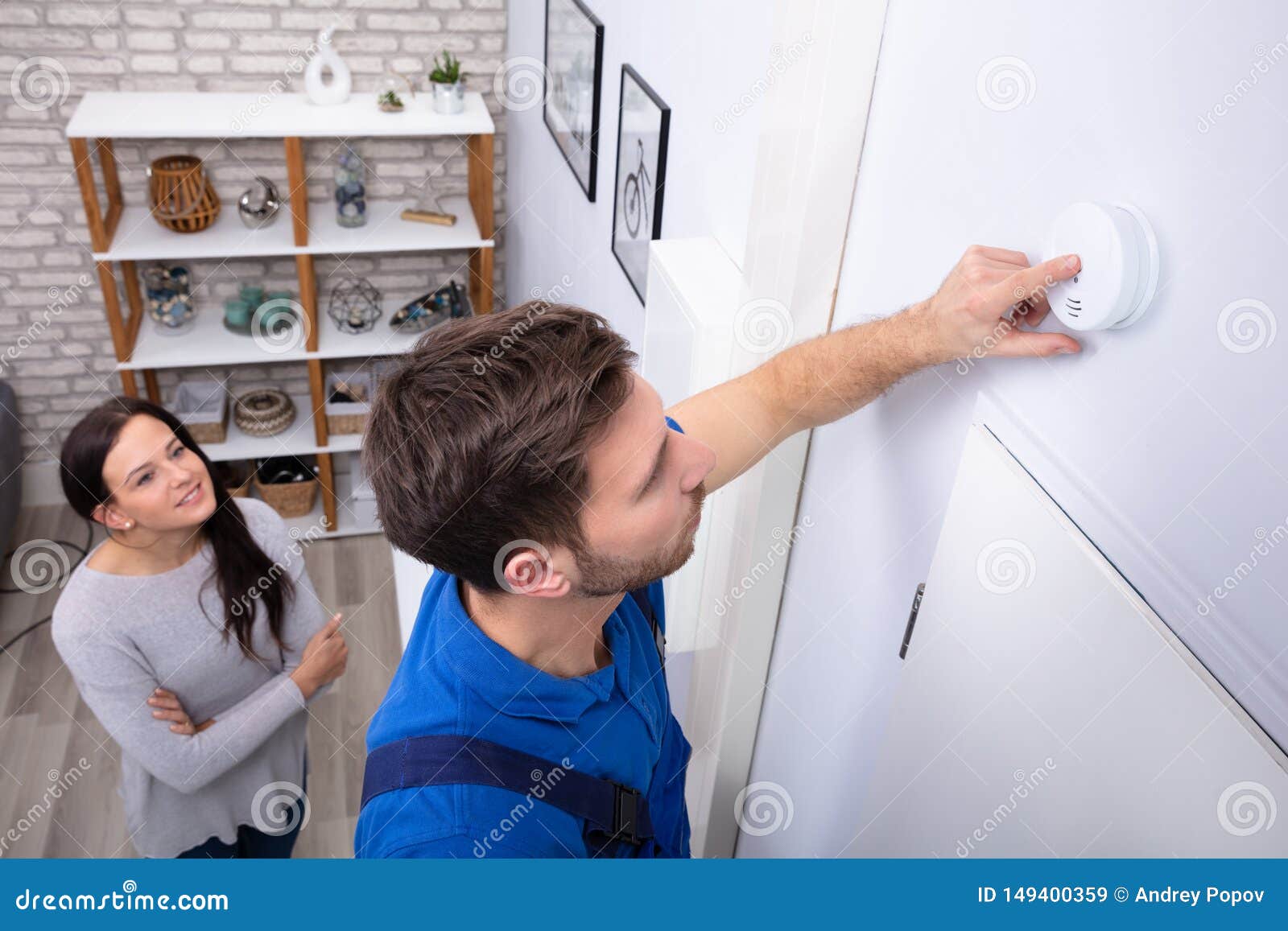 repairman installing smoke detector on wall