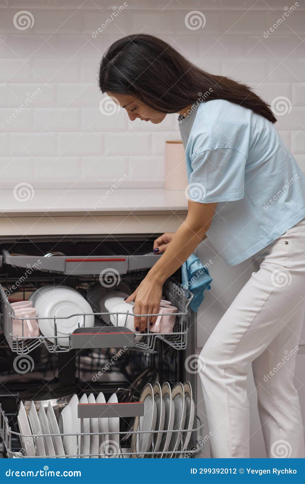 Pretty Woman Unloading from Open Dishwasher Machine with Clean Utensils