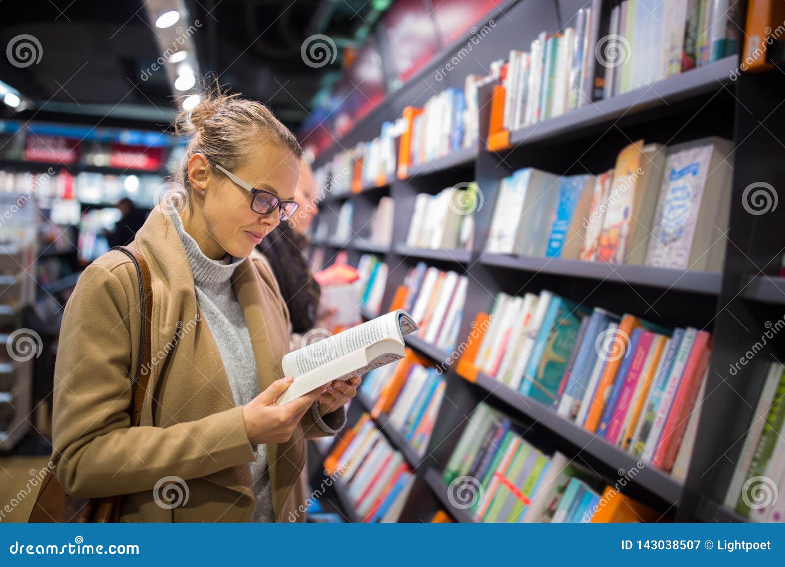pretty, young female choosing a good book to buy
