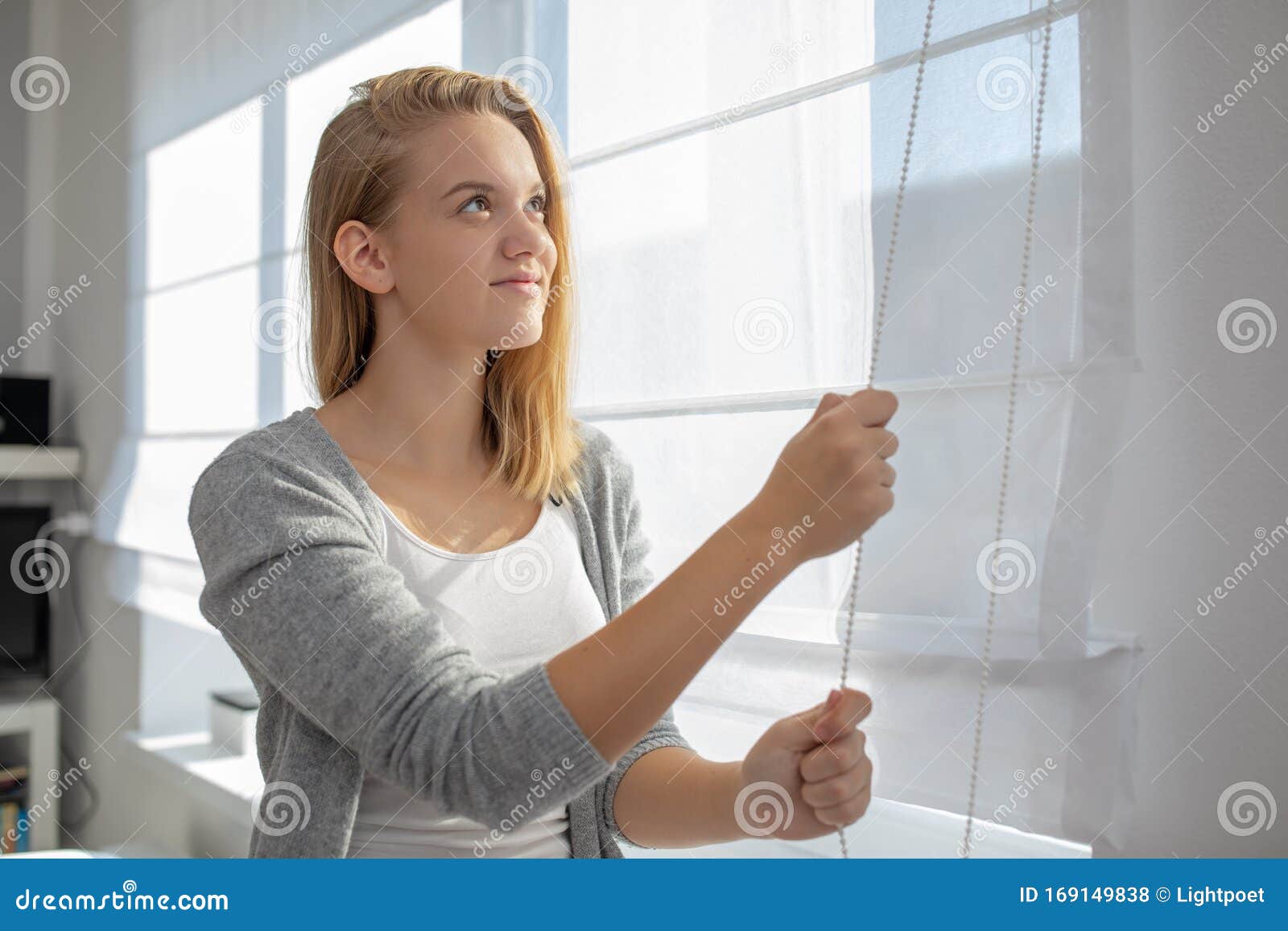 pretty, young woman lowering the interior shades/blinds