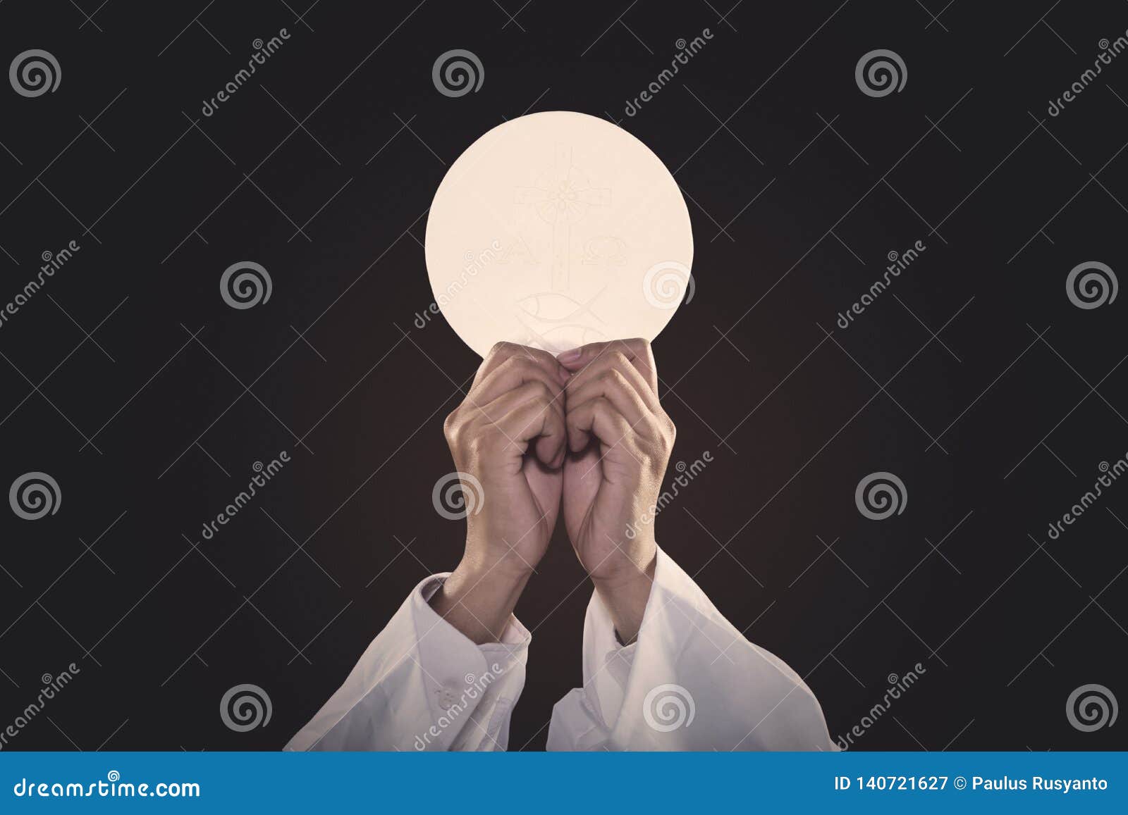 priest hands lifting a communion bread