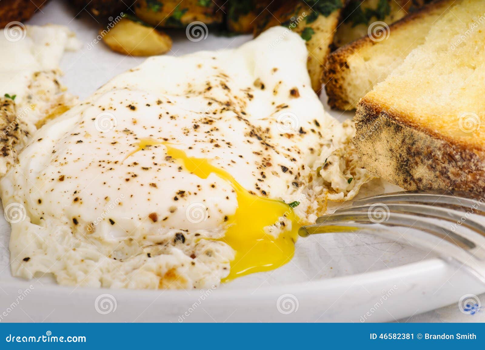 Prima colazione di domenica. Prima colazione indulgente di bacon, delle patate tritate della patata, delle uova laterali soleggiate e del pane tostato del lievito naturale