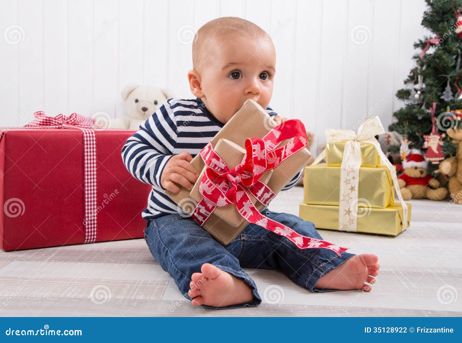 Primeiro Natal: bebê que desempacota um presente. Primeiro Natal: bebê que desempacota uma caixa de presente vermelha