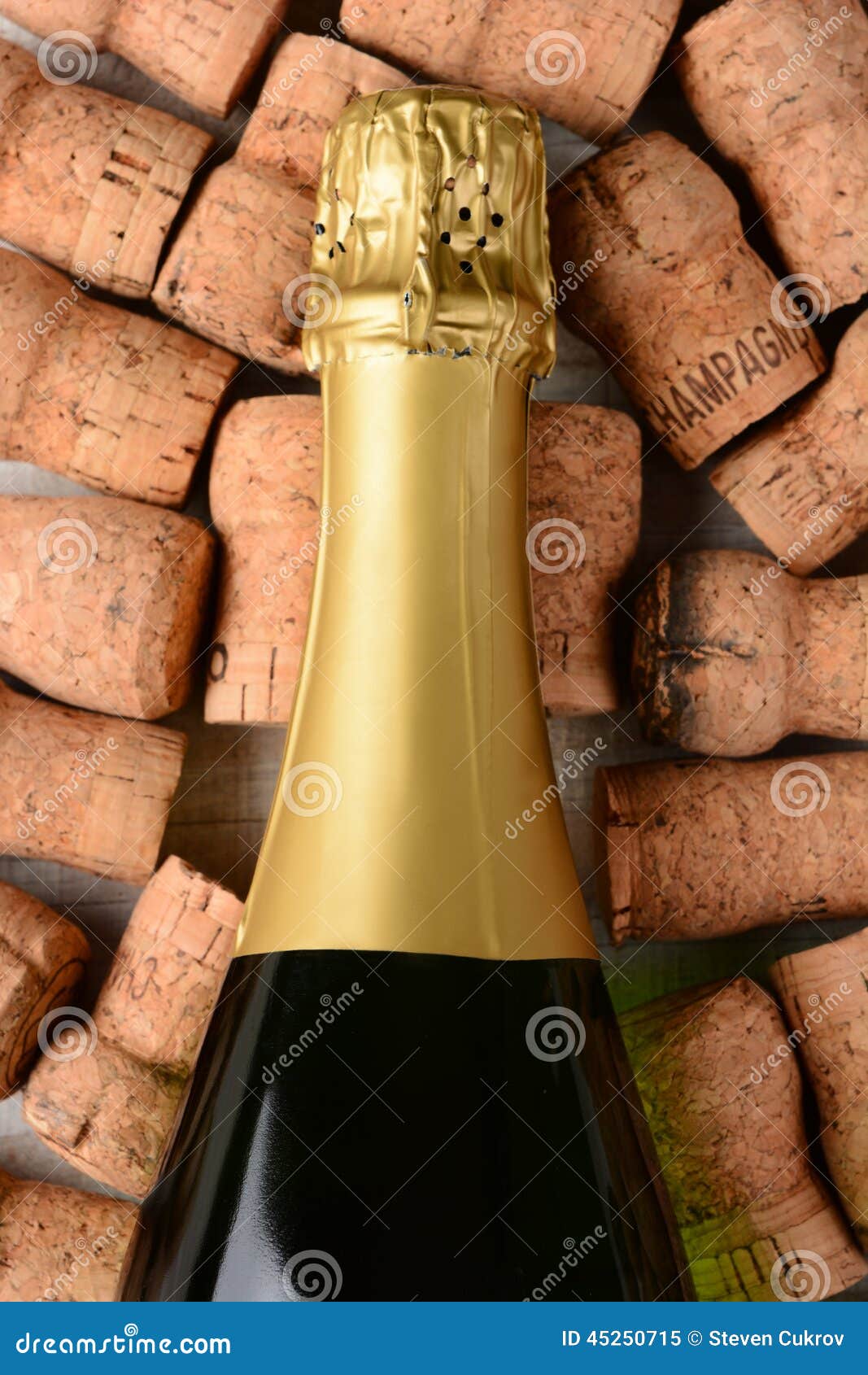 Primer Champagne Bottle Corks. Tiro del primer del alto ángulo de una botella del champán que pone en su lado encima de corchos usados viejos Formato vertical en un fondo de madera blanco rústico
