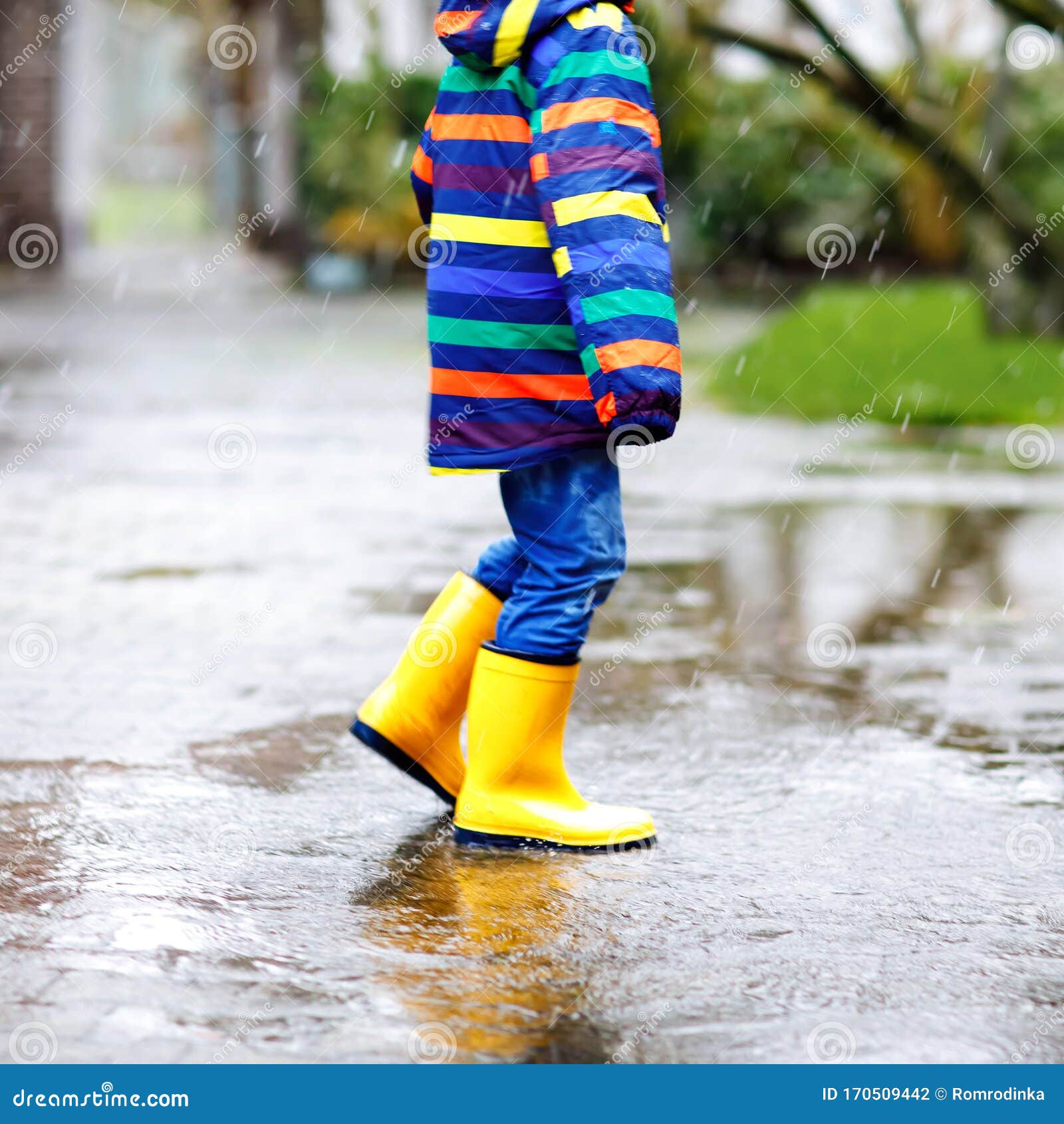 Primer Plano De Un Niño Que Lleva Botas De Lluvia Amarillas Y Camina Durante El Sueño, La La Nieve En El Día Frío Niño D Foto de archivo - Imagen