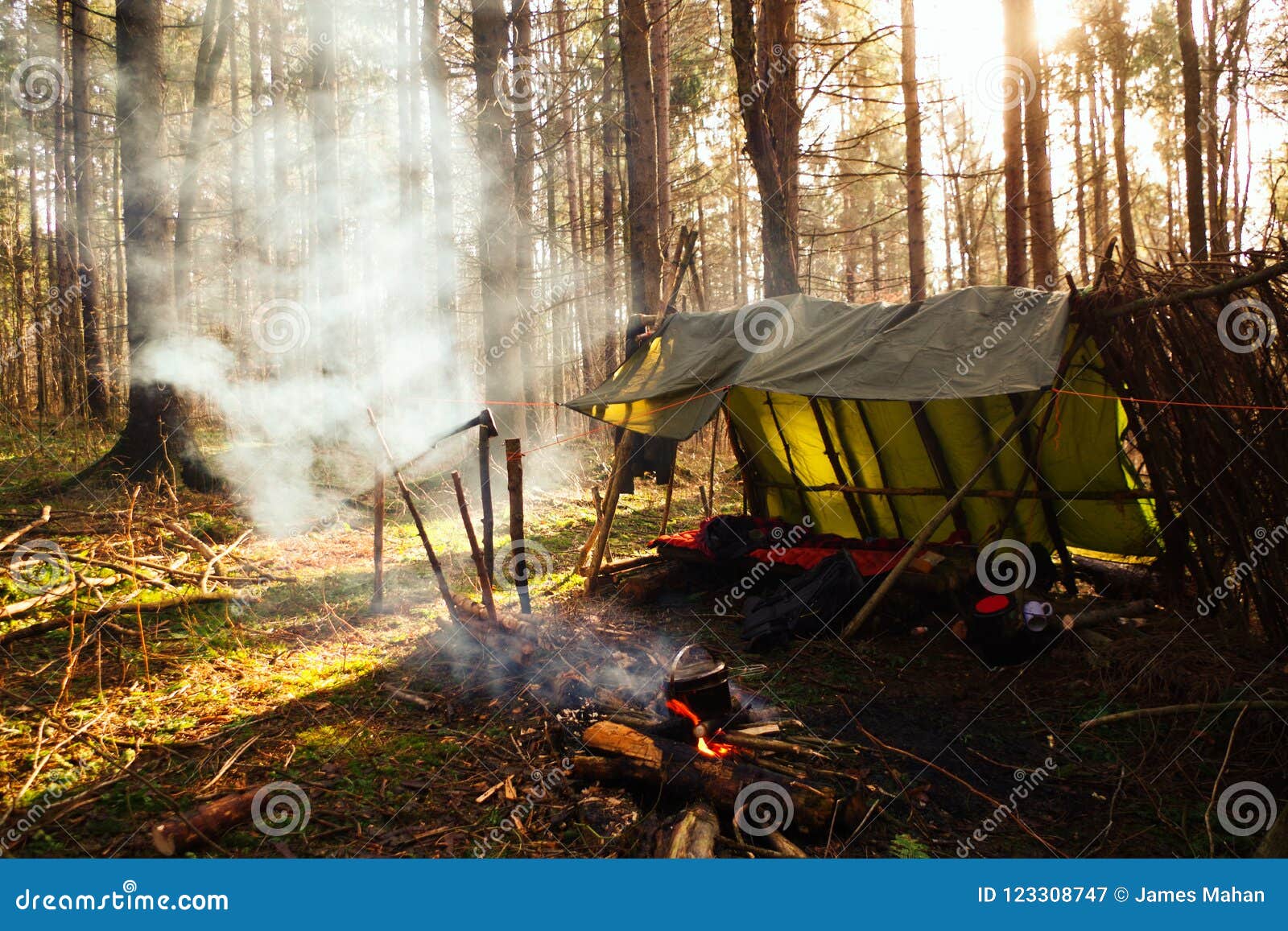 primitive bushcraft lean to shelter with campfire in the wilderness.