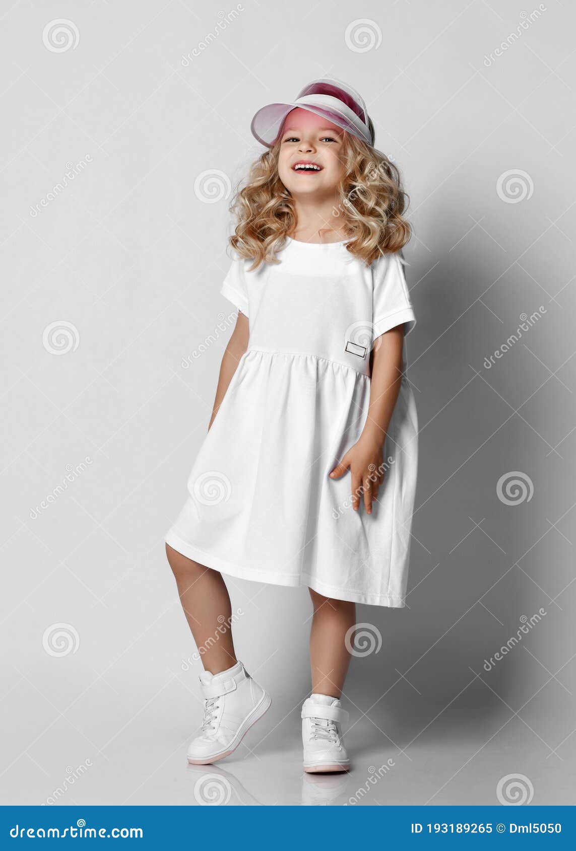 De Niña Rubia Rubia Y Rizada Con Vestido Blanco Casual Y Zapatillas De Tenis Pie Sobre Una Pared Gris Imagen de archivo - Imagen de peinado, feliz: 193189265