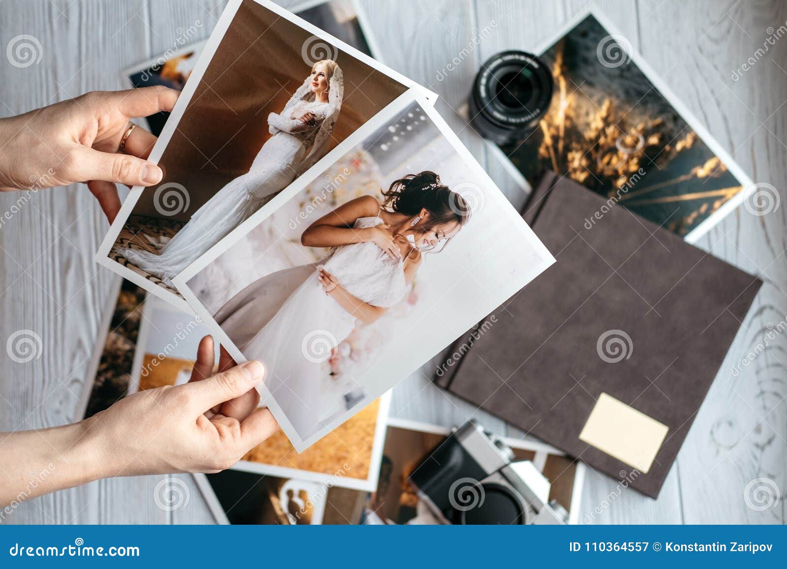 printed wedding photos with the bride and groom, a vintage black camera, photoalbum and woman hands with two photos