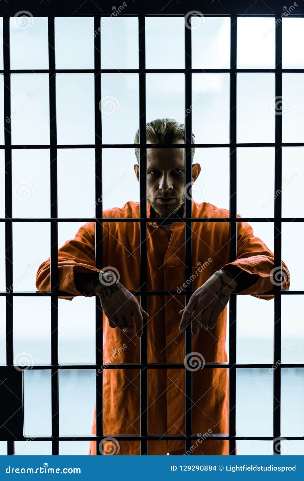 Prisoner Putting Hands between Prison Bars and Looking Stock Photo