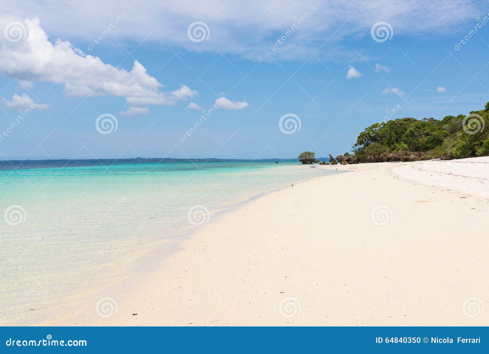 pristine white tropical beach with blue sea and lush vegetation