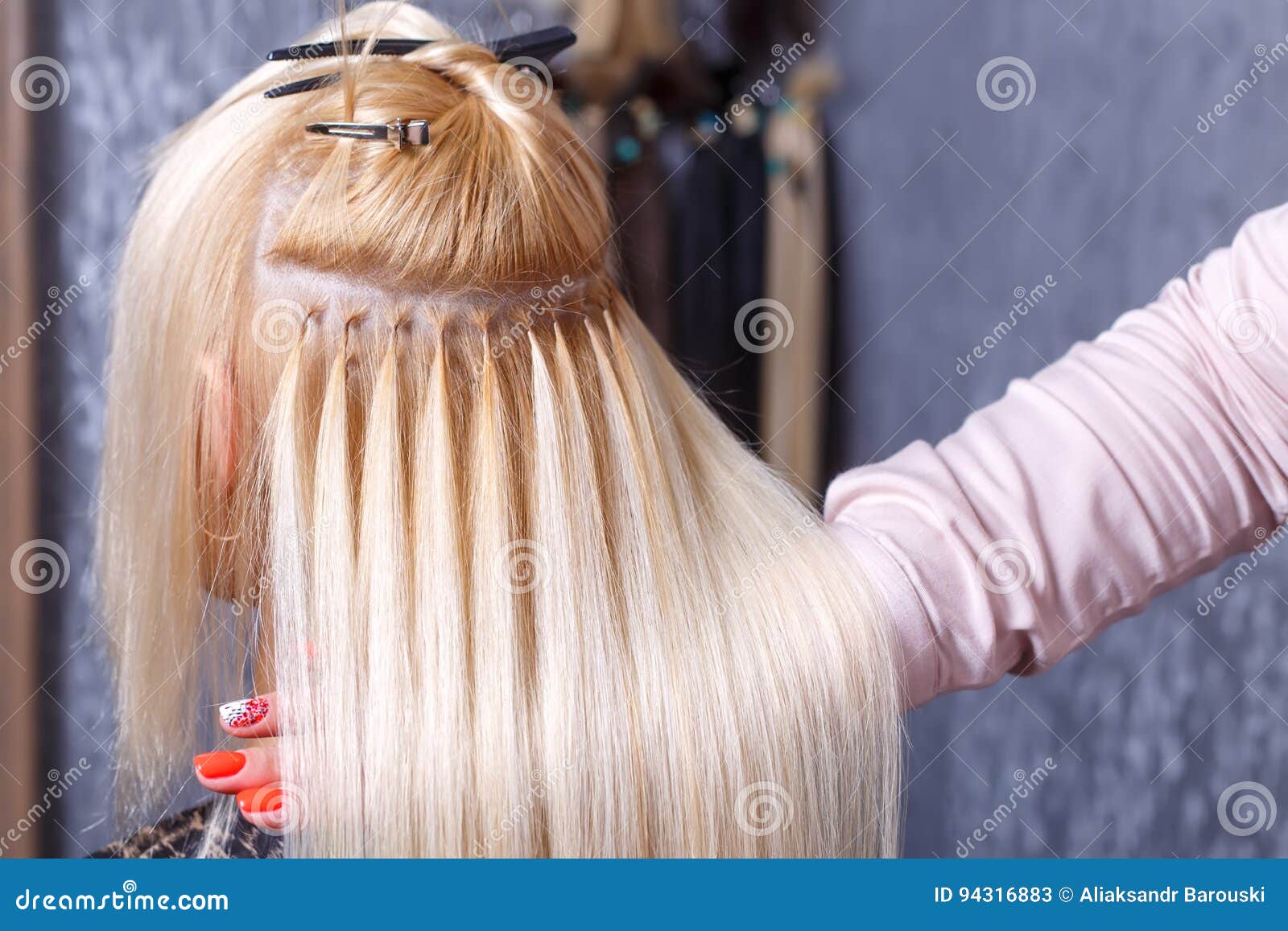 Procedimento das extensões do cabelo O cabeleireiro faz extensões do cabelo à moça, louro em um salão de beleza Foco seletivo. O cabeleireiro faz extensões do cabelo a uma moça, um louro em um salão de beleza Cuidados capilares profissionais Foco seletivo