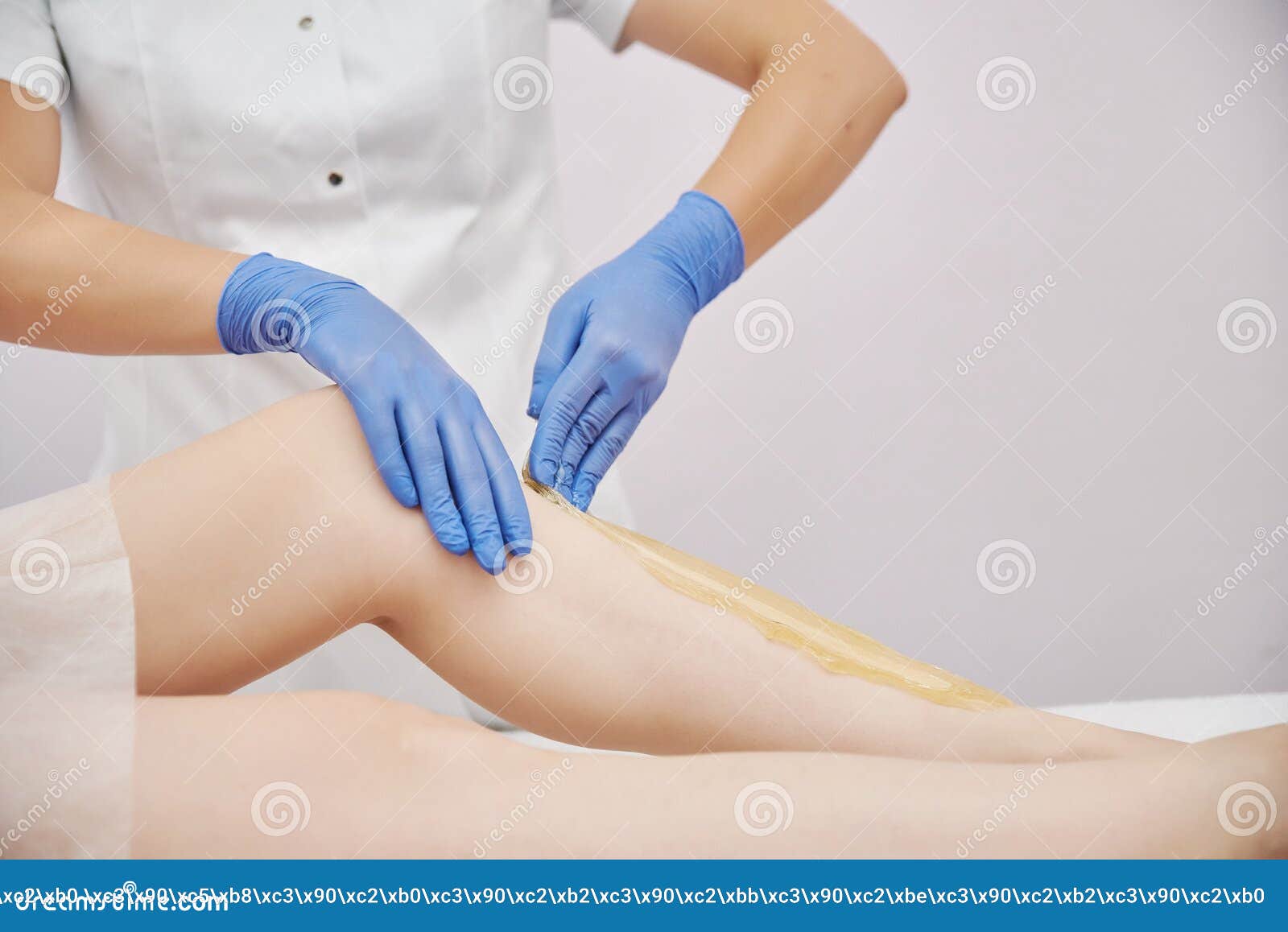 the procedure shugaring. master in blue medical gloves apply sugar paste with his hands