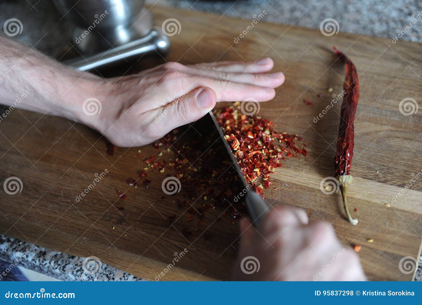 The Process of Chopping Chili Pepper with Man`s Hands. Stump in the