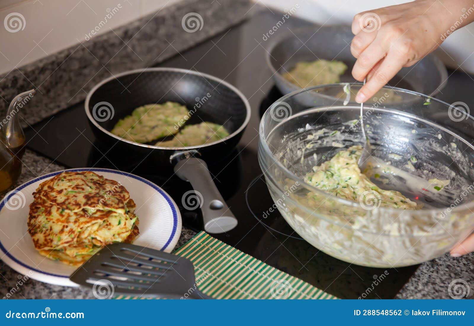 Process Frying Zucchini Pancakes in Frying Pan in Kitchen Stock Photo
