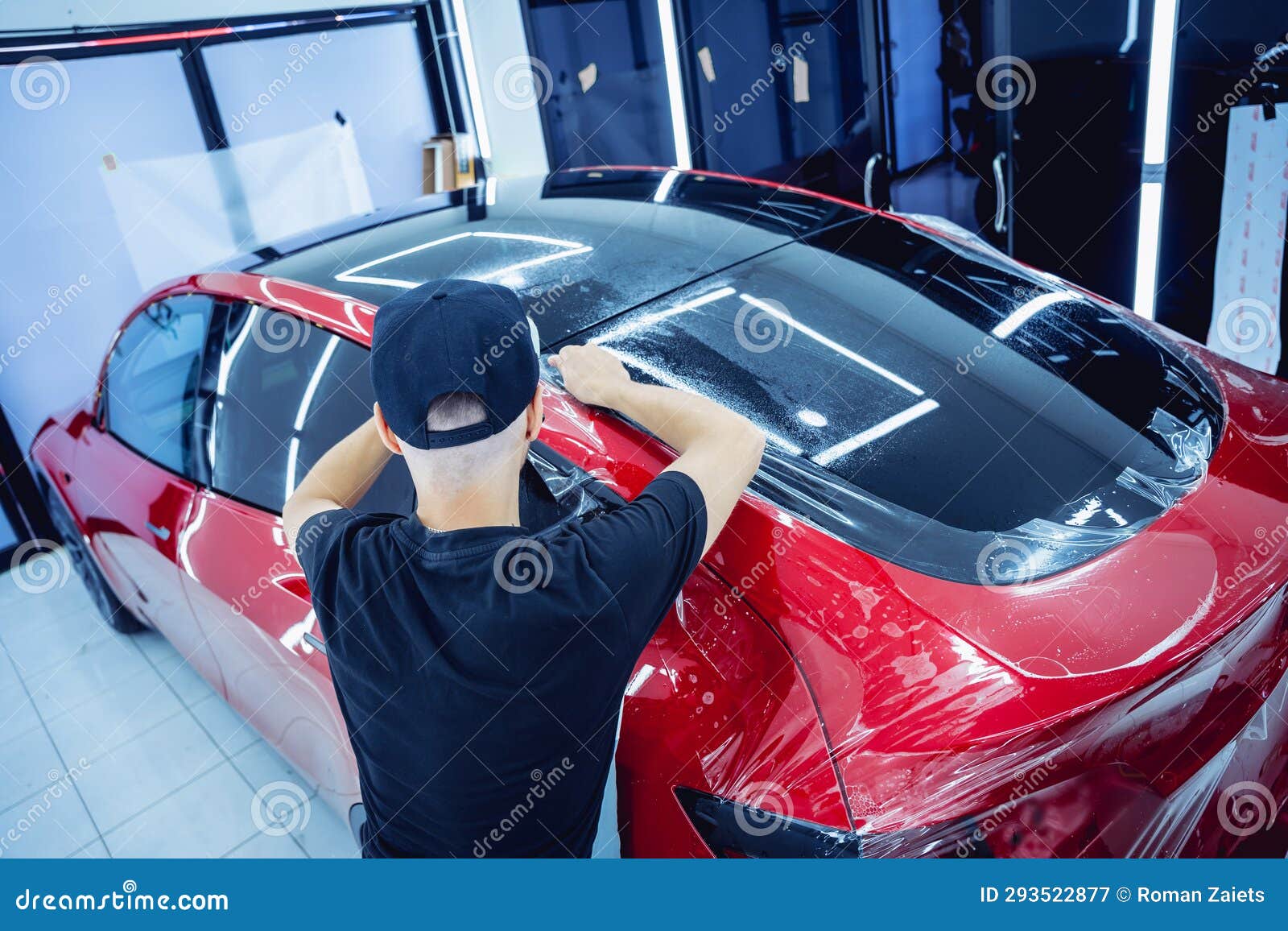 The Process of Installing Protective Film on the New Red Car. Stock