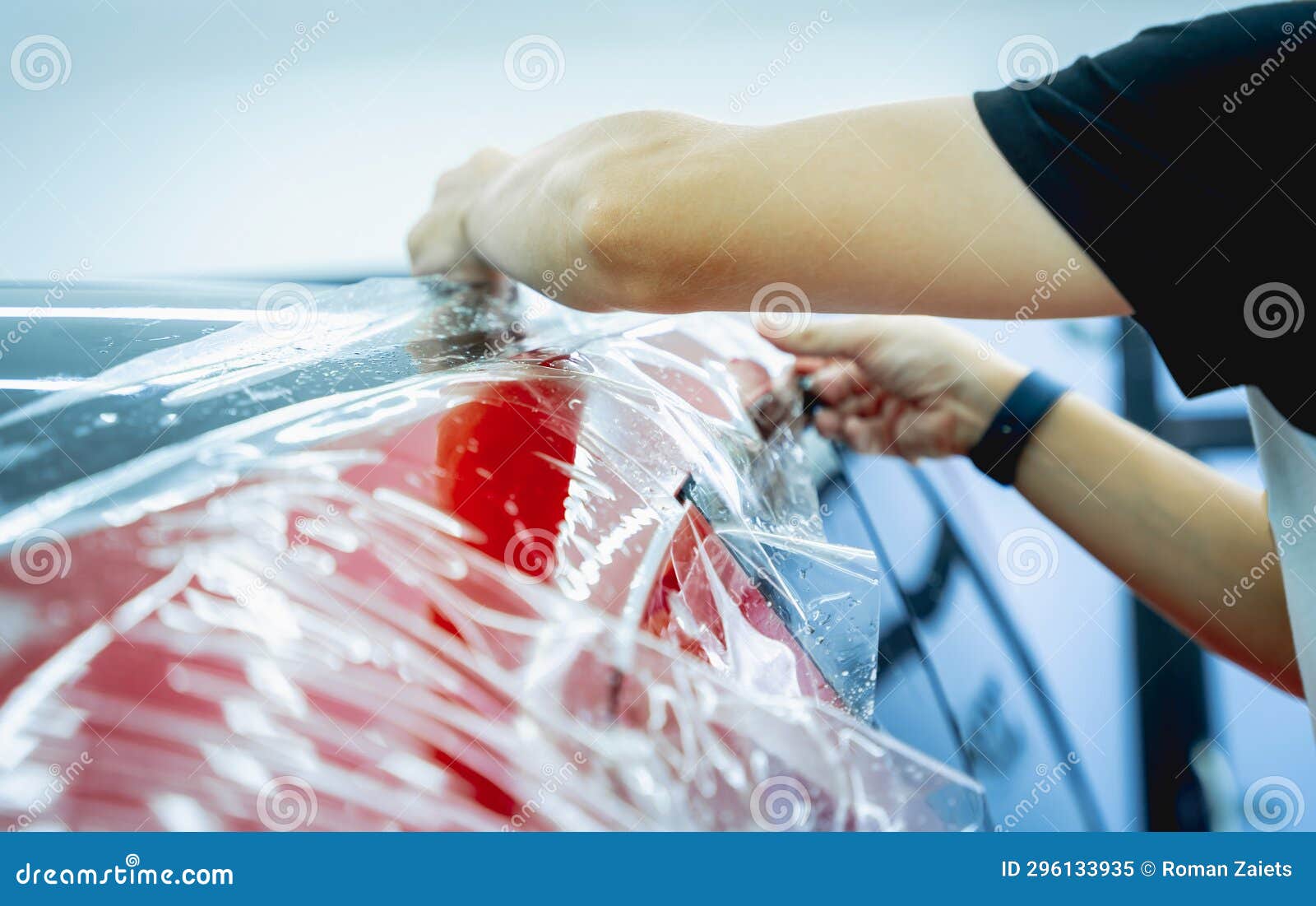 The Process of Installing Protective Film on the New Red Car. Stock