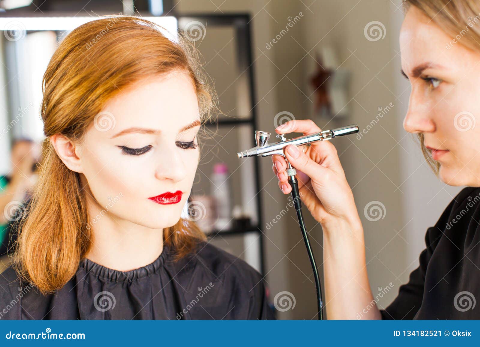 Side view of a make-up artist using aerograph making an airbrush