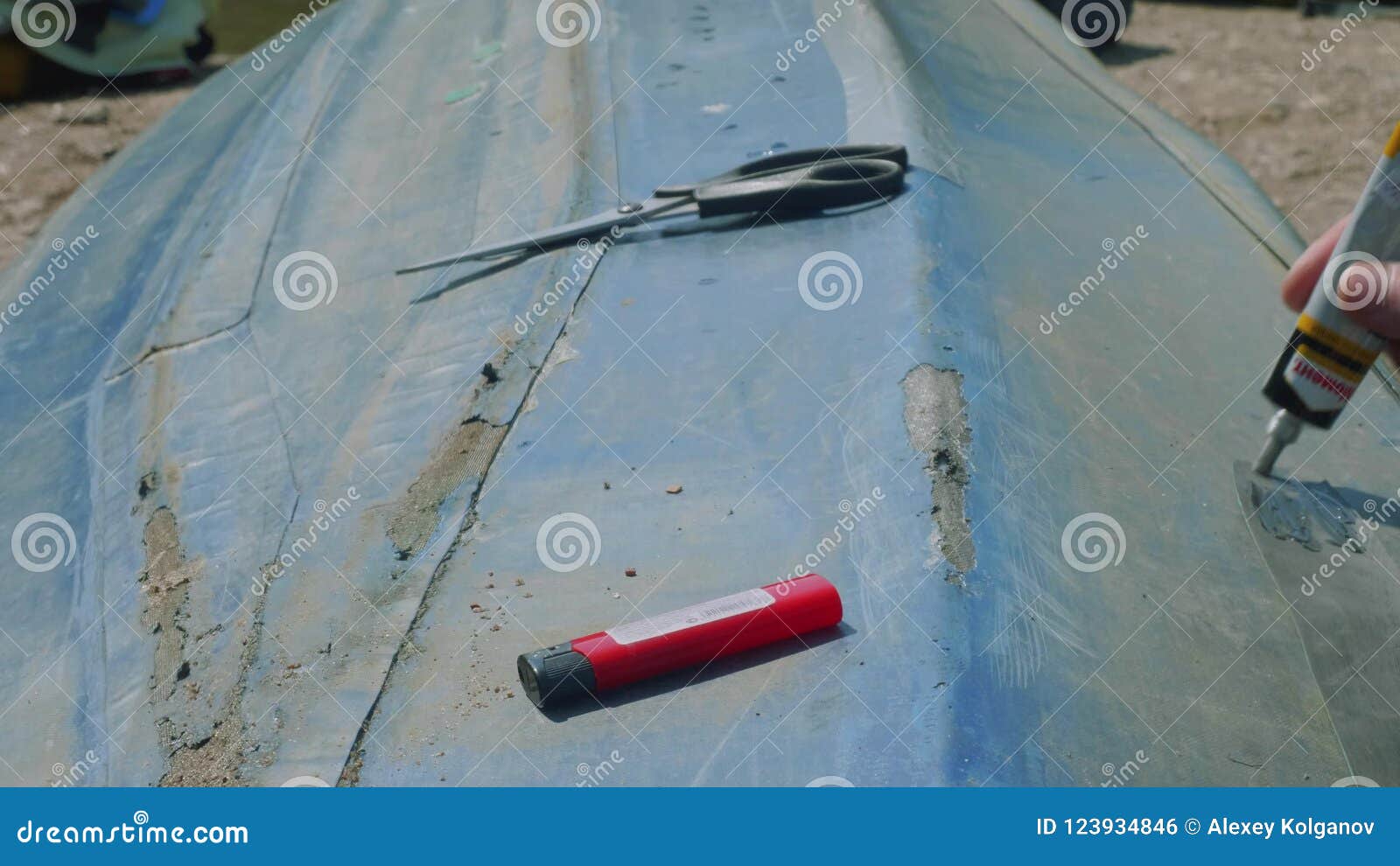 Process of Reparing Canoe. Man Tapes Hole on Bottom of Canoe Stock