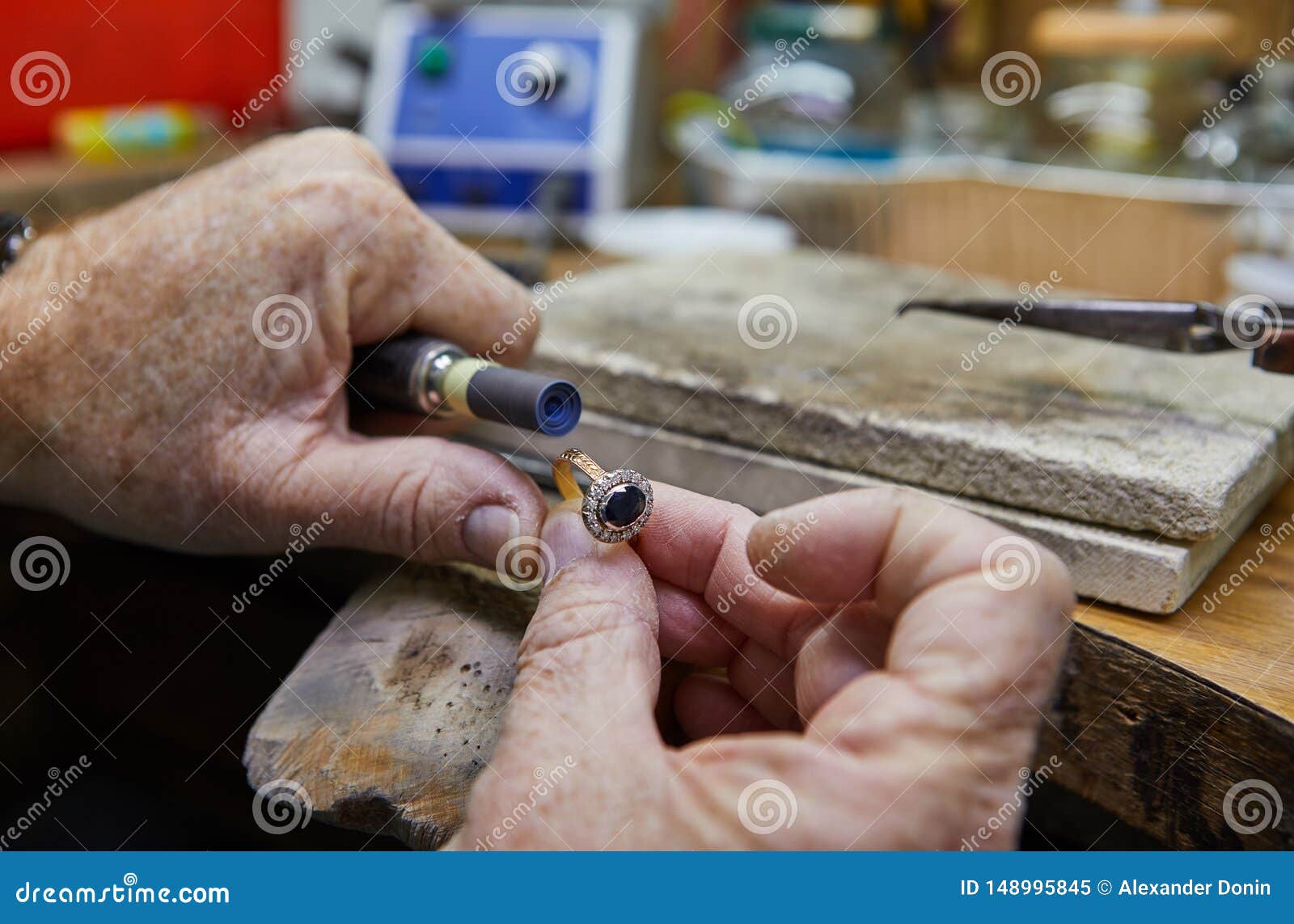 Producci?n de la joyer?a El joyero pule un anillo de oro. Jewelry production. Jeweler polishes a gold ring on an old workbench in an authentic jewelry workshop