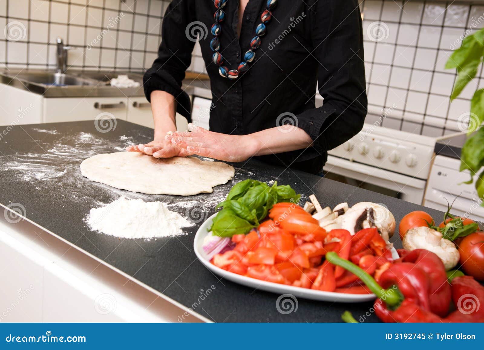 Produrre la pasta della pizza. Una pasta di fabbricazione femminile della pizza nel paese nella cucina sul contatore.