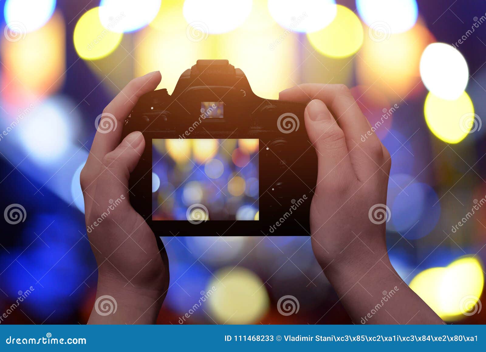 profesional digital camera in hands. blue and yellow bokeh in background