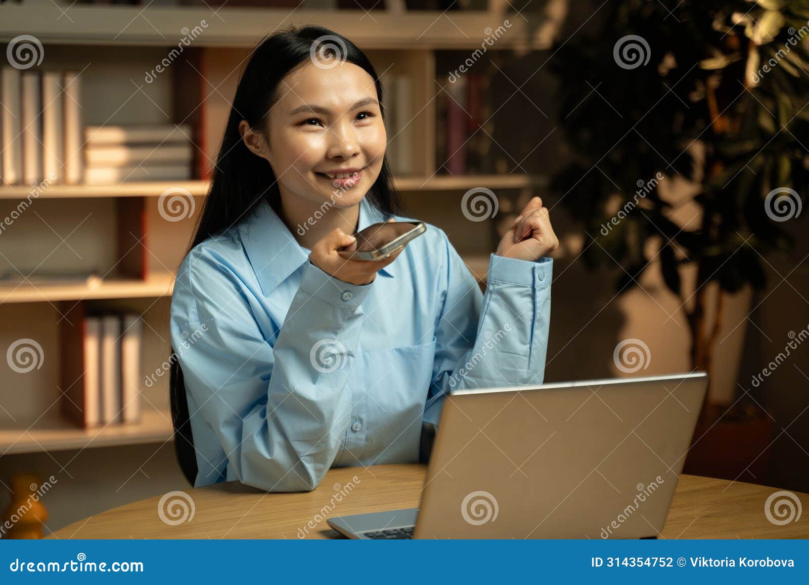 professional asian woman in blue shirt holding conference call during evening office hours