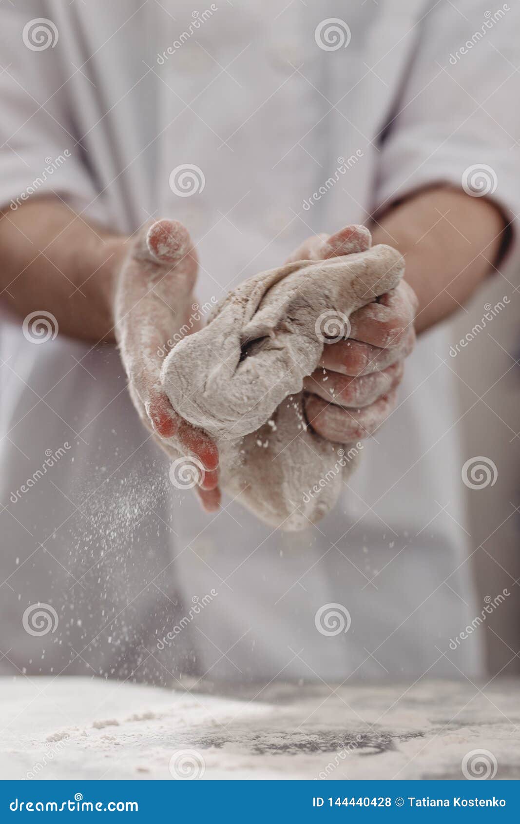 Professional Baker Kneads Dough in His Hands in the Kitchen of the