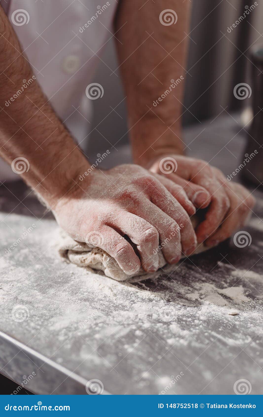 Professional Baker Kneads Dough on the Table in the Kitchen of the