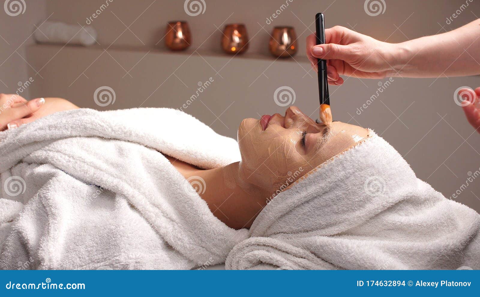 Professional Beautician Applying Cosmetic Mask On Female Face In Beauty