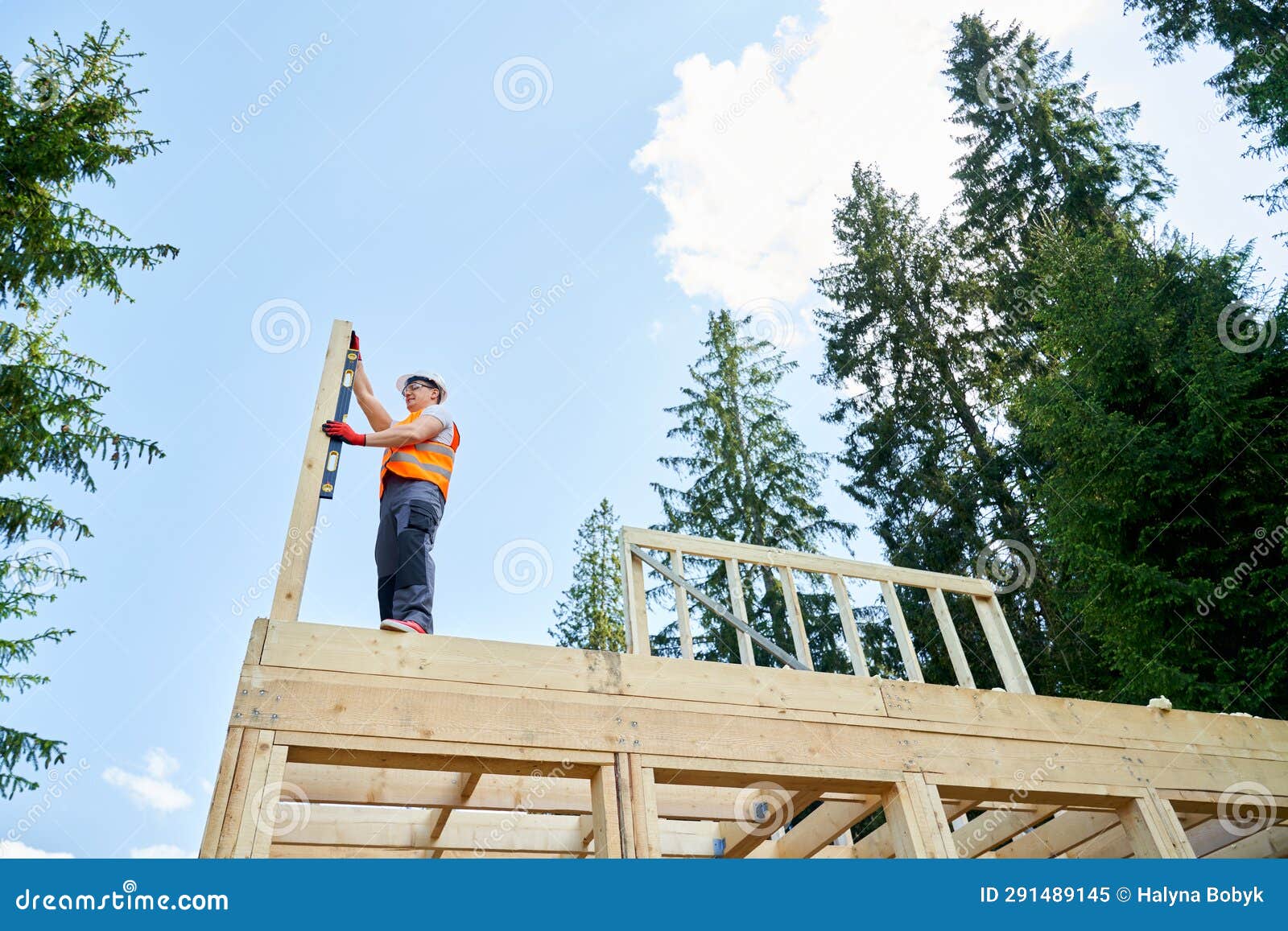 professional builder standing high, holding, putting, measuring wooden gilder.