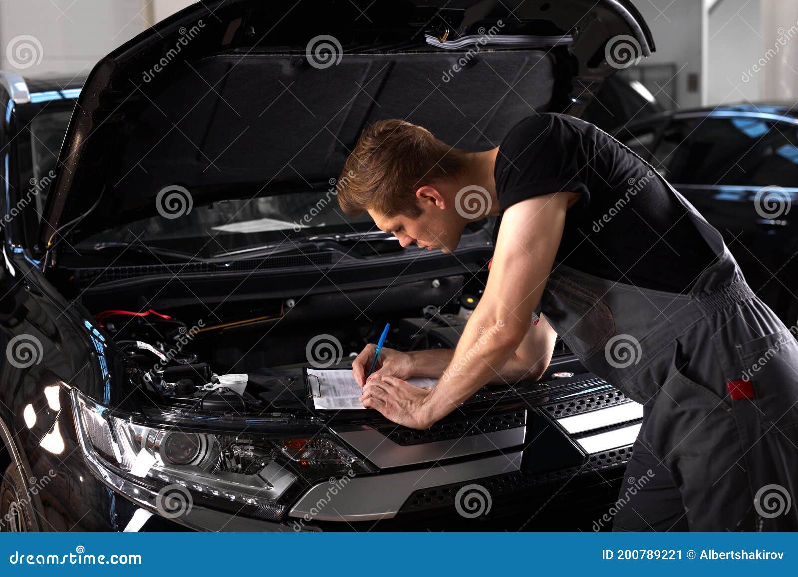 Professional Car Mechanic is Examining Engine Under the Hood at Auto