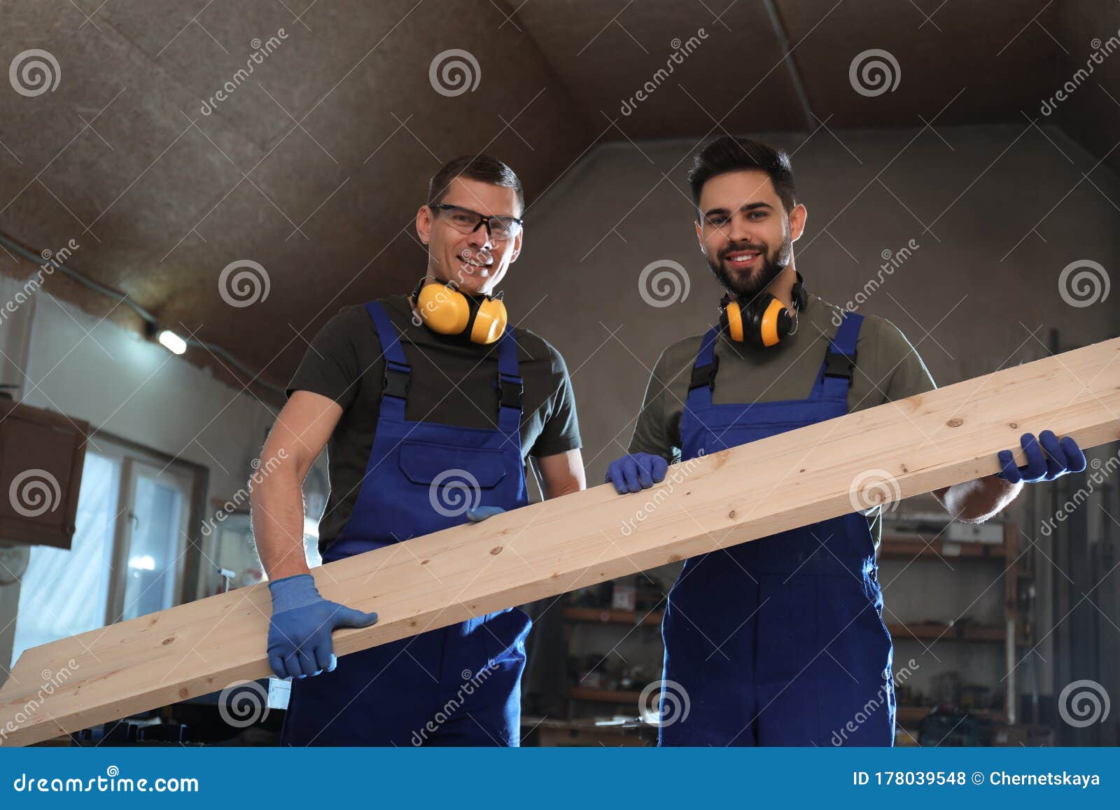 Professional Carpenters with Large Board in Stock Photo