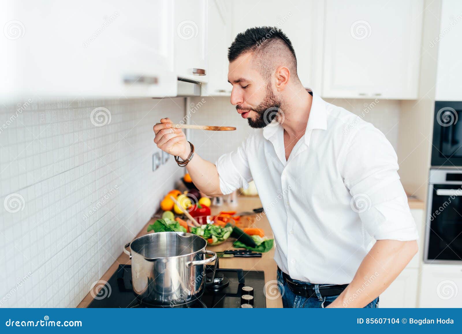 Professional Chef Cooking in White Kitchen, Tasting and Adding Salt and