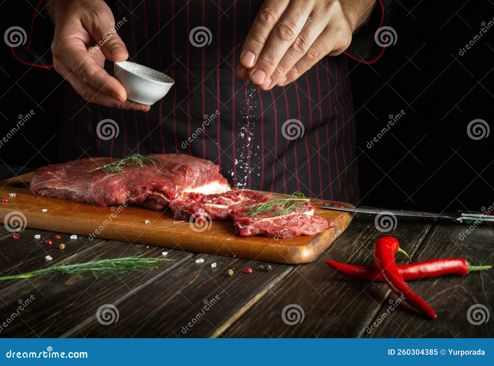 Professional Chef Salts Raw Fresh Beef before Roasting or Grilling