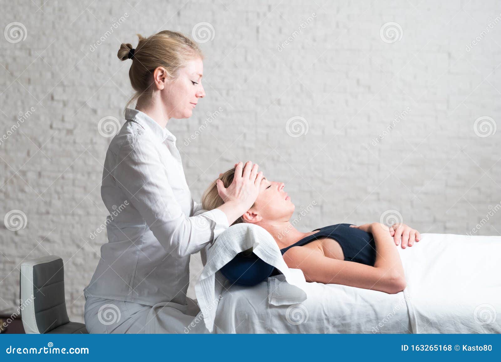 Professional Female Masseur Giving Relaxing Massage Treatment To Young Female Client Hands Of