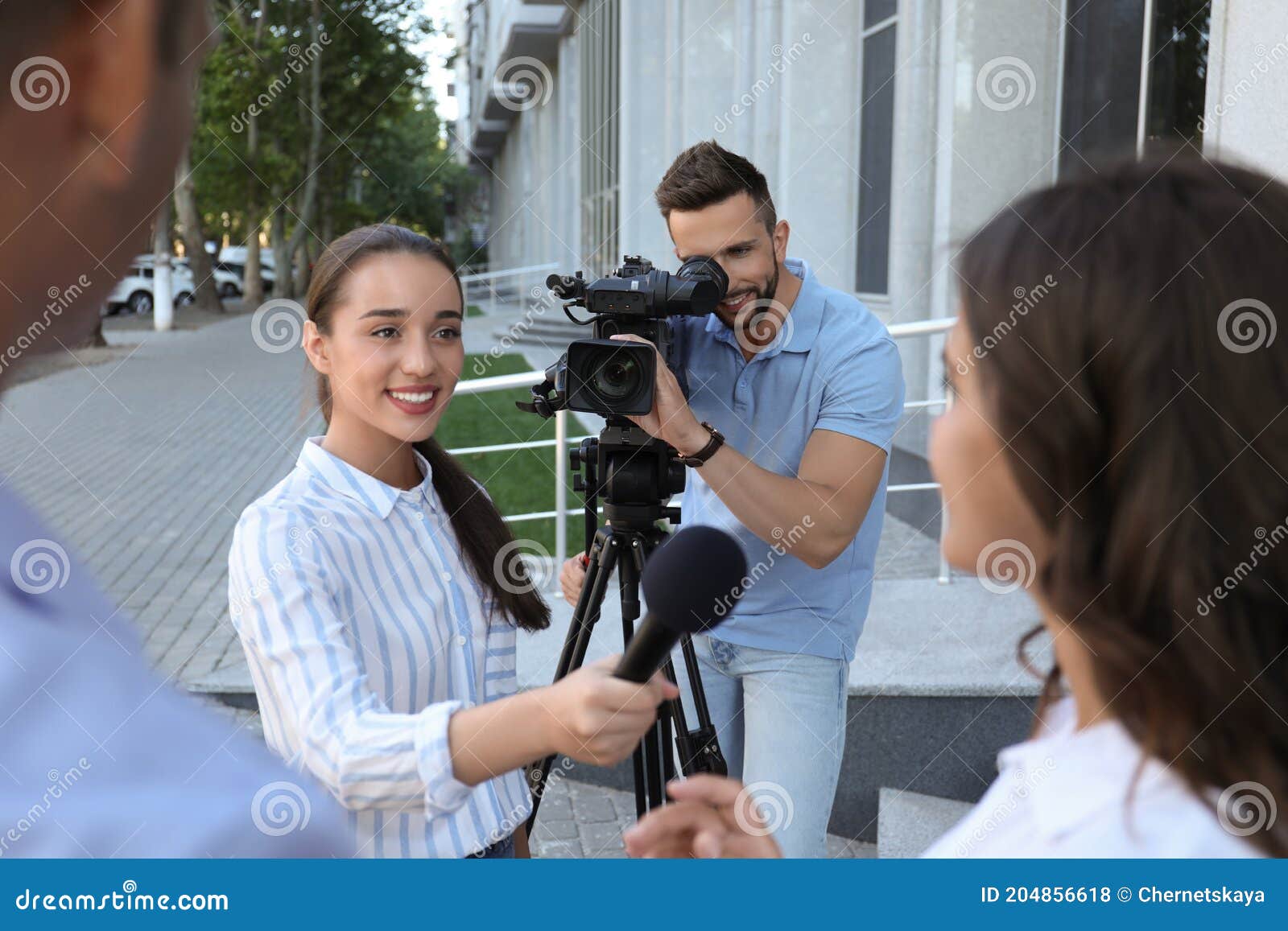 professional journalist and operator with video camera taking interview outdoors