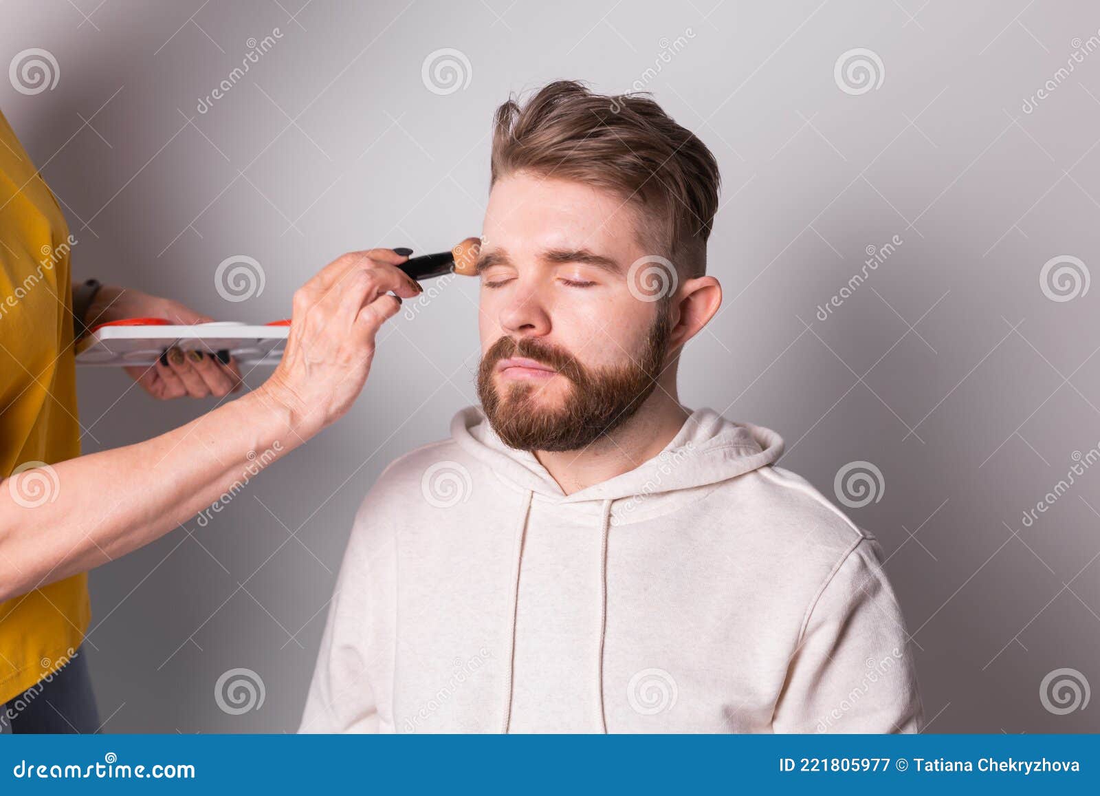 Professional Makeup Artist Doing Young Man Makeup in Studio Stock