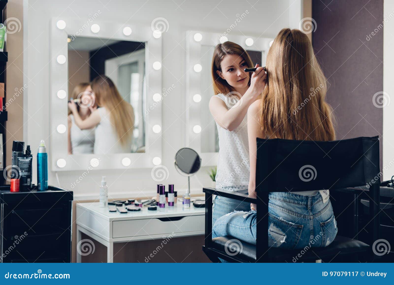 professional makeup artist working on young girl creating natural look in beauty salon